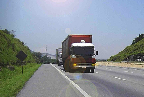 Foto traz imagem de caminhões em uma rodovia.